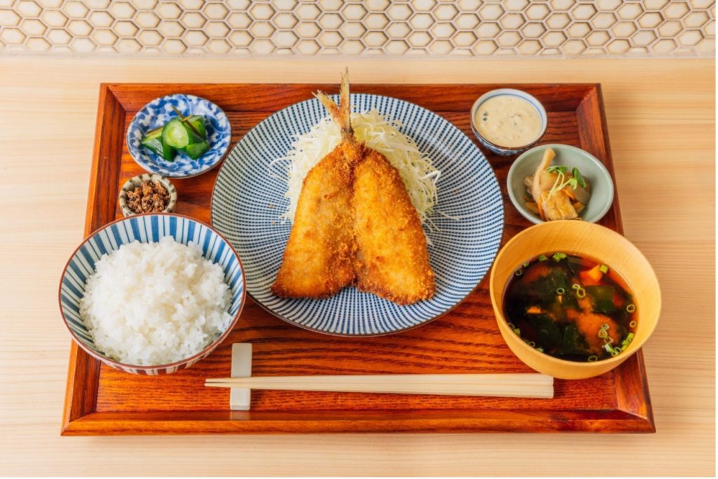「アジフライ定食」(1,480円)
脂のりが良い長崎県松浦市の真鯵を使用したアジフライ。
新鮮な鯵を店内で捌き、オーダーが入り次第丁寧に揚げます。きゅうりのシャキシャキとした食感がアクセントの自家製タルタルソースを付けてお召し上がりください。
